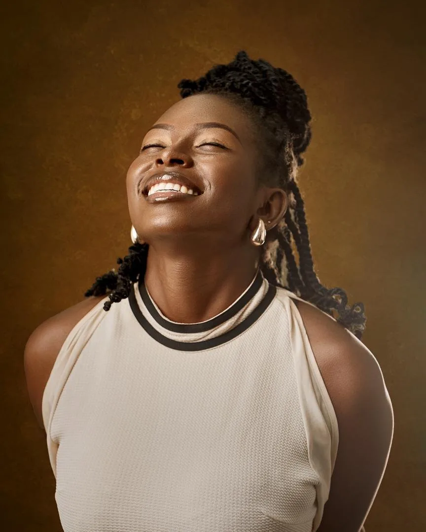 Doria laughing, head tilted back, in a studio portrait